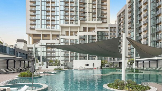 A modern hotel with a rooftop pool, lounge areas, and a view of high-rise buildings.