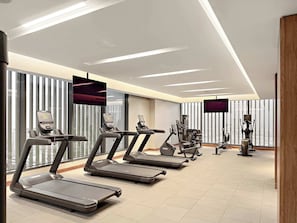 A gym with treadmills, stationary bikes, and a rowing machine.