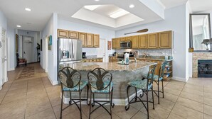 A spacious kitchen with a central island, wooden cabinets, and a large window. - The Moorings 101 (Orange Beach)