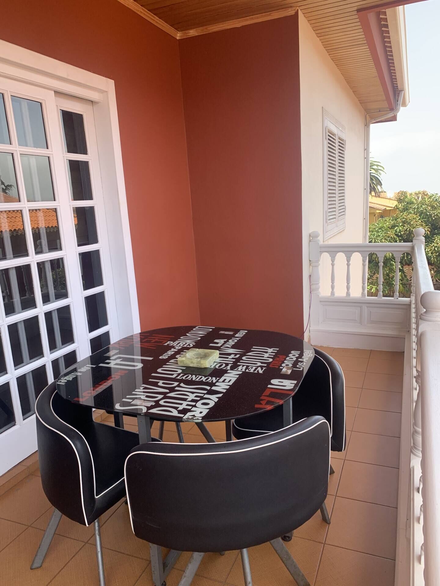 A round table with chairs on a balcony, surrounded by a white railing.