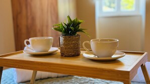 A wooden table with two white cups and a small potted plant.