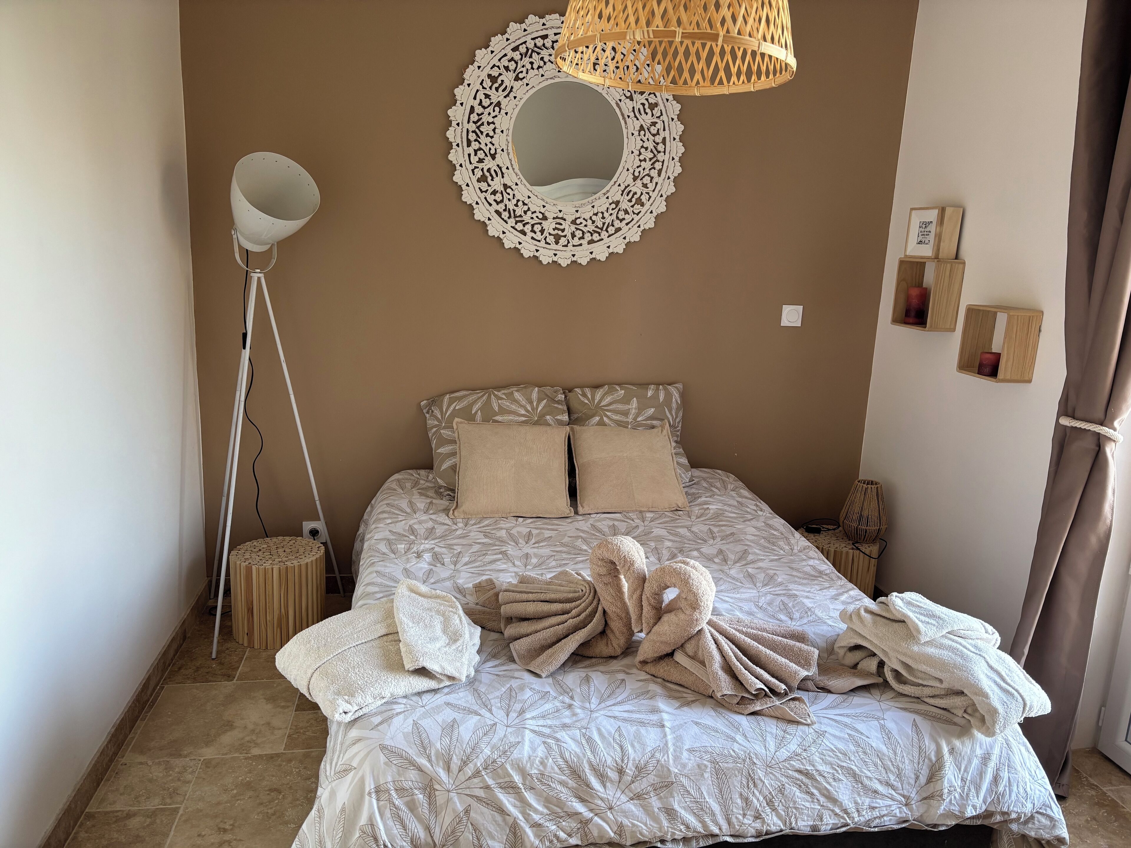 Ein Schlafzimmer mit einem Bett, einem großen Spiegel, einer Stehlampe und einem Nachttisch.