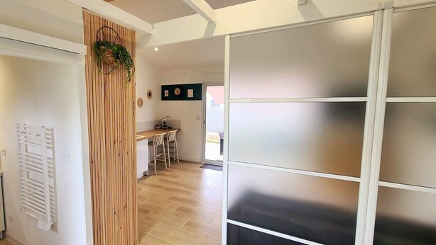 A hallway with a wooden partition, a white radiator, and a door leading to a room. - STUDIO 30 M2 (Labastide-Saint-Sernin)