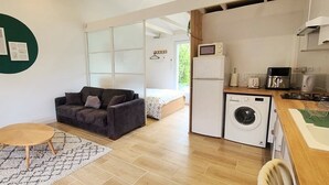 A compact living space with a sofa, a small round table, a washing machine, and a kitchenette with a microwave and toaster. - STUDIO 30 M2 (Labastide-Saint-Sernin)