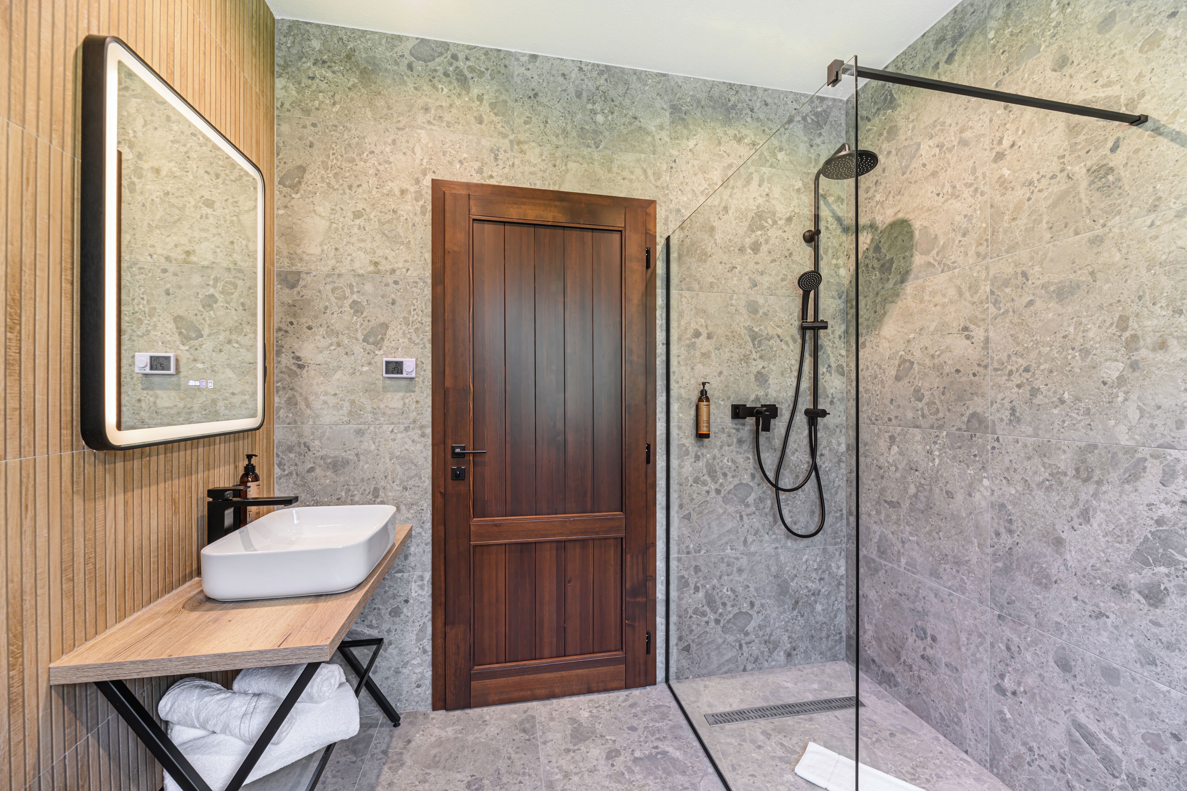 A bathroom with a wooden door, a white sink, and a shower area.