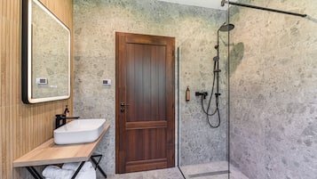 A bathroom with a wooden door, a white sink, and a shower area.