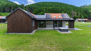 Ein modernes Gebäude mit einer großen Holzkonstruktion und einer Glasfassade, eingebettet in einen bewaldeten Hang.