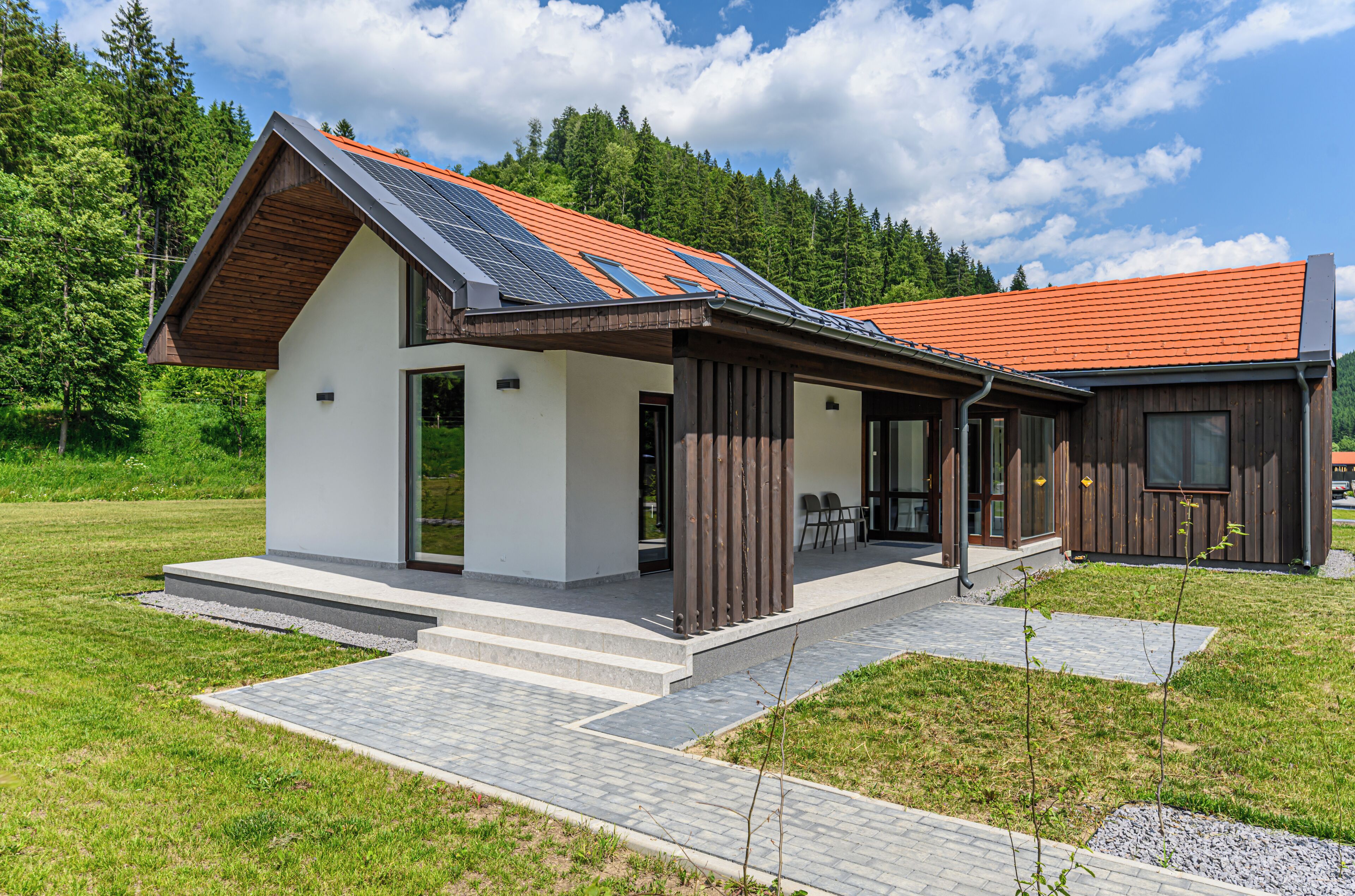 Ein modernes Haus mit Satteldach, Solaranlage und überdachter Veranda.