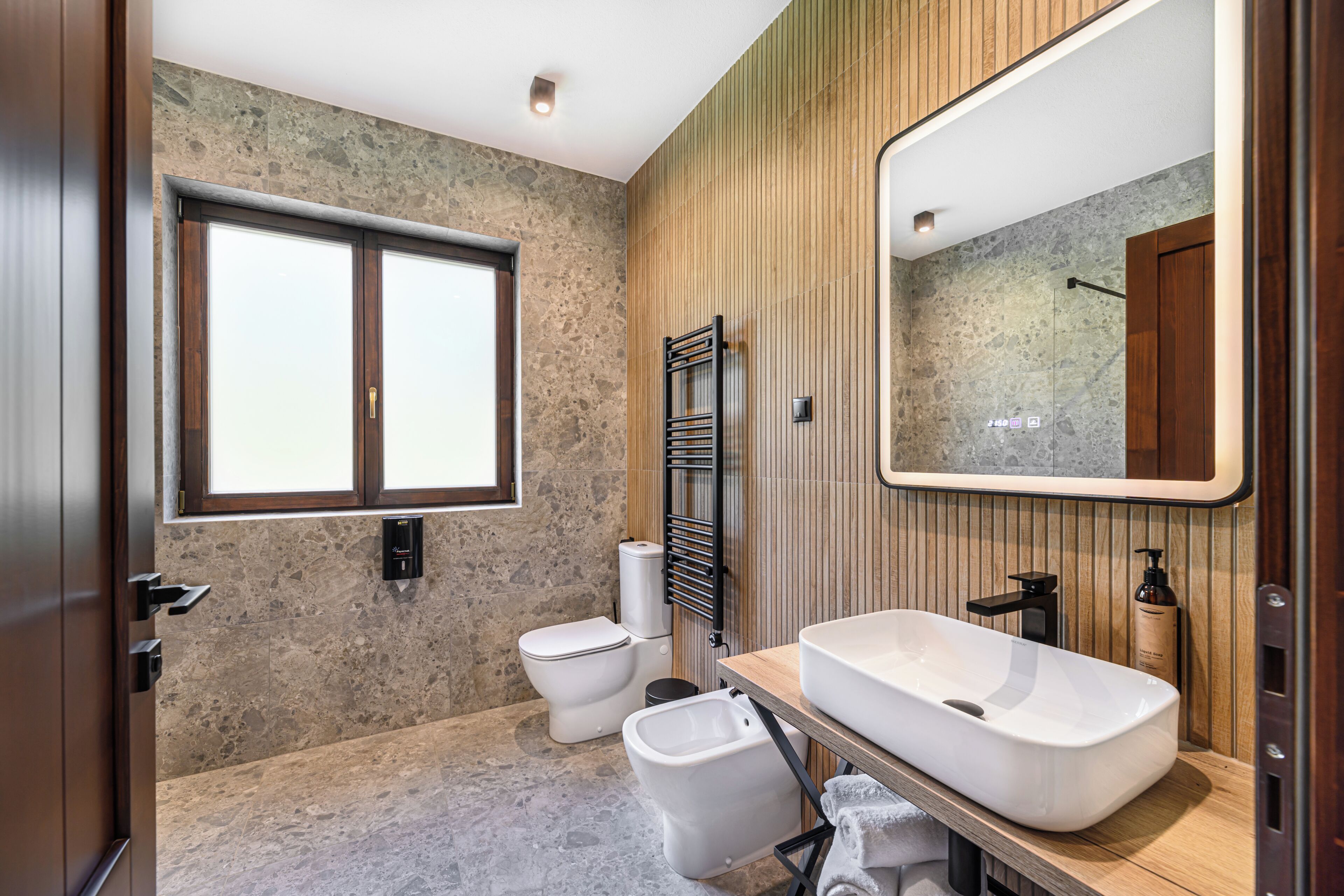 Un bagno moderno con un'ampia finestra, un lavabo sospeso e un water.