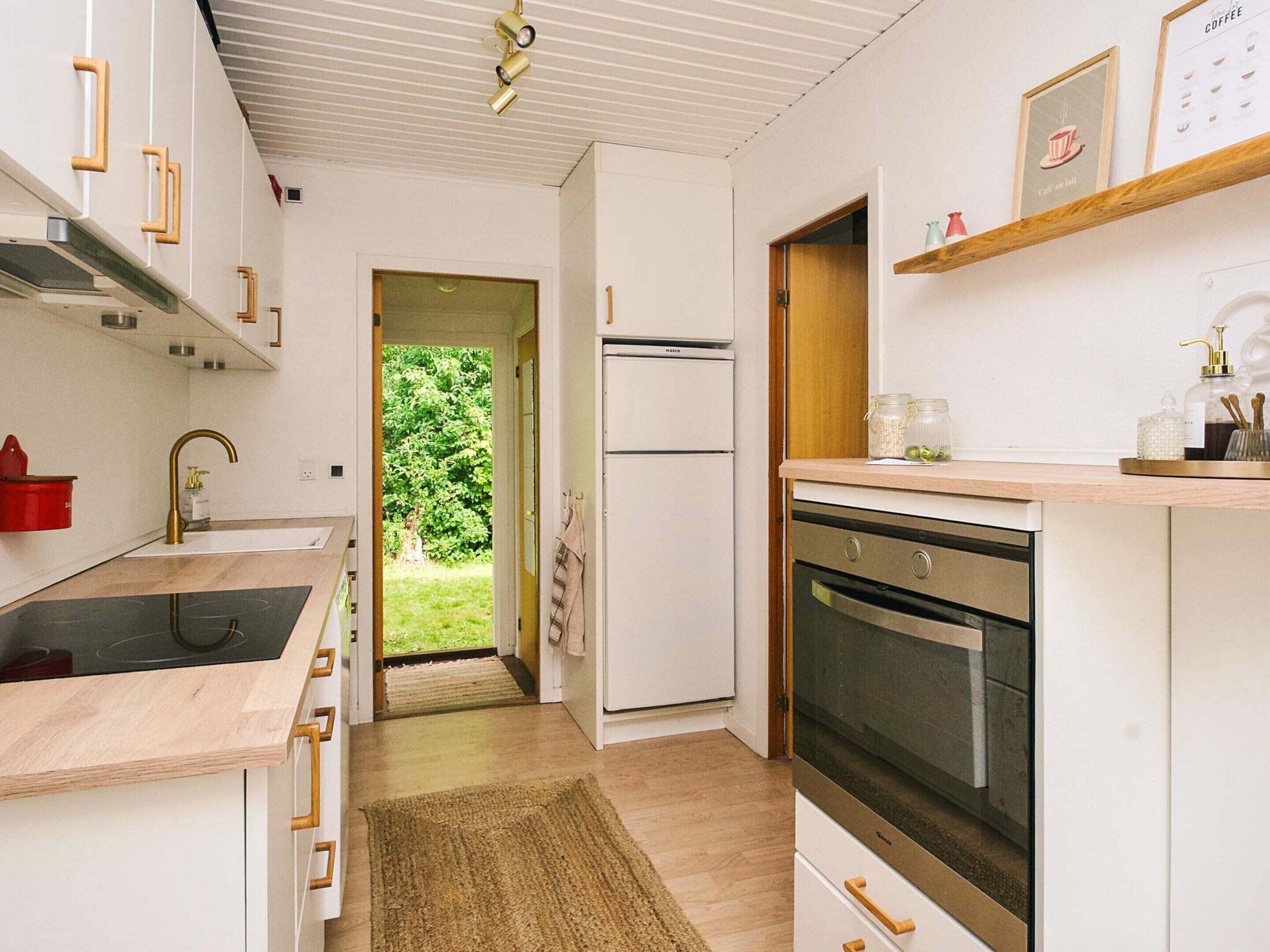 Een moderne keuken met witte kasten, een ingebouwde oven en een roestvrijstalen afzuigkap.