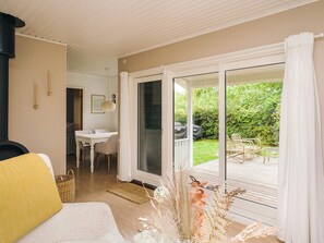 A room with a bed, a dining table, and a view of a garden through a sliding glass door.