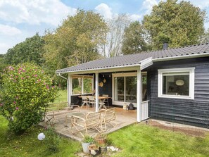 A house with a covered patio, outdoor furniture, and a garden.