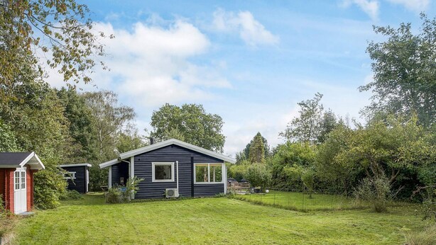 Une maison à l’extérieur sombre, avec un petit garage attenant et une pelouse bien entretenue.