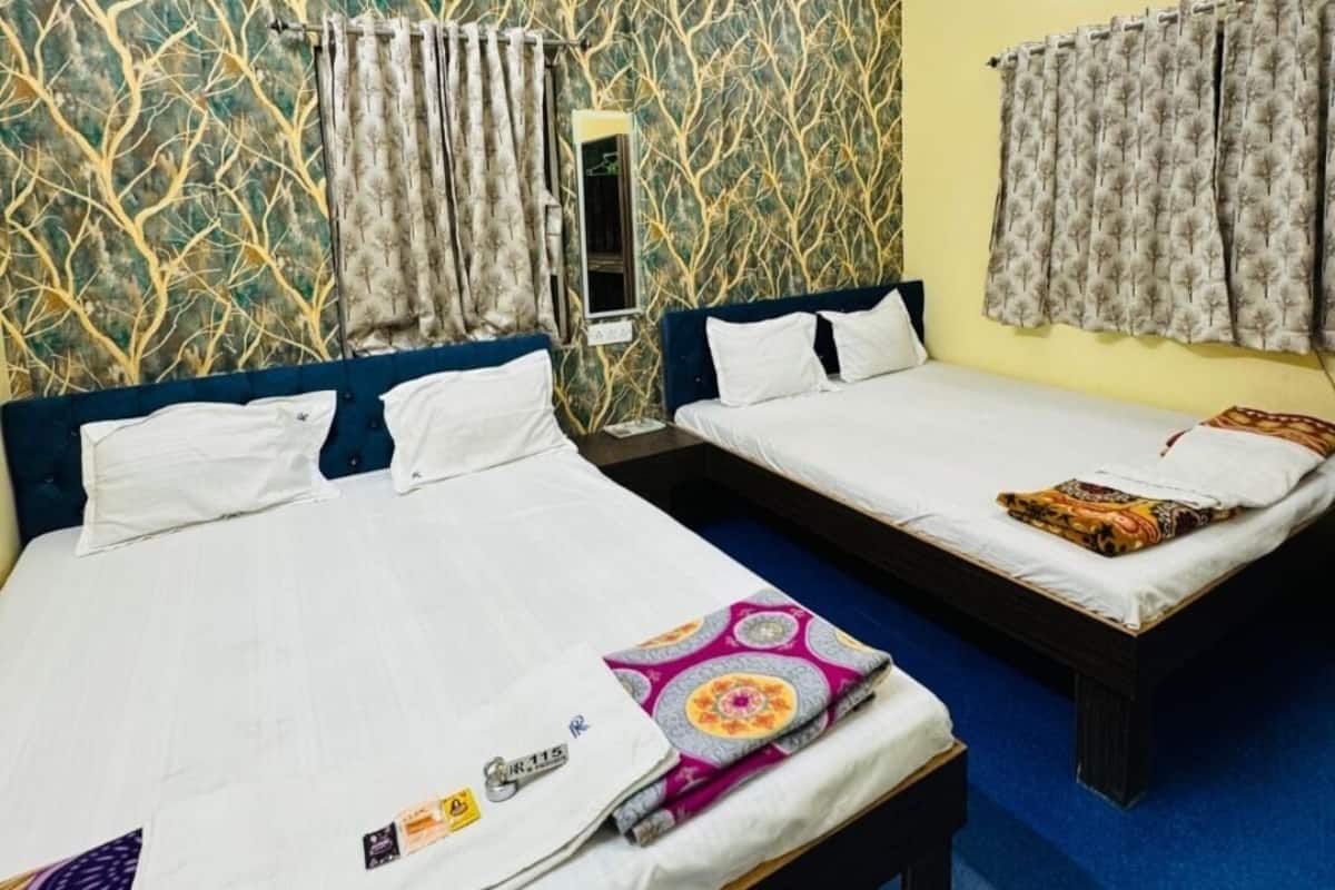 Une chambre d’hôtel avec deux lits, un ventilateur de plafond, un mur à motifs et une fenêtre avec des rideaux.