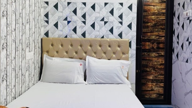 A bedroom with a tufted headboard, a bed with white linens, a blue towel, and a brown patterned blanket. - RR GUEST HOUSE (Kolkata)