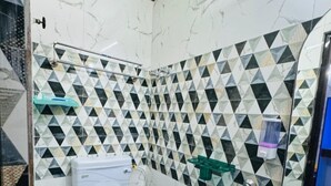 A bathroom with a toilet, a sink, and a shower. The walls are tiled with a geometric pattern. - RR GUEST HOUSE (Kolkata)