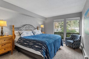 A bedroom with a bed, two bedside tables with lamps, a chair, and large windows with a view. - Steps from Lake Dillon & Amphitheater - Central to 3 World-Class Ski Resorts! (Dillon)