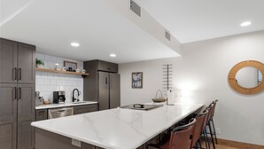 A modern kitchen with grey cabinets, a white marble island, and a round mirror on the wall. - Modern Mountain-View Condo - Pool, Hot Tubs & Near 3 Ski Resorts! (Frisco)