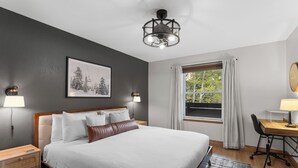 A neatly arranged hotel room with a large bed, a desk, and a window with curtains. - Modern Mountain-View Condo - Pool, Hot Tubs & Near 3 Ski Resorts! (Frisco)