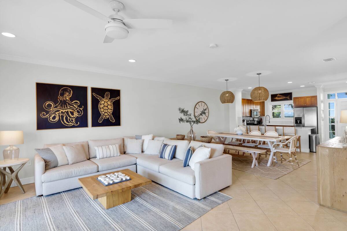 A modern living room with a sectional sofa, a wooden coffee table, and a dining area with a white table and chairs.