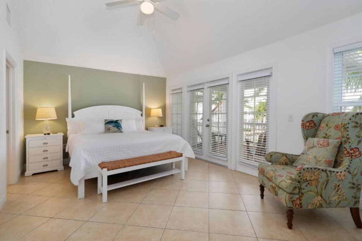 A bedroom with a bed, bedside tables, a chair, and a ceiling fan.