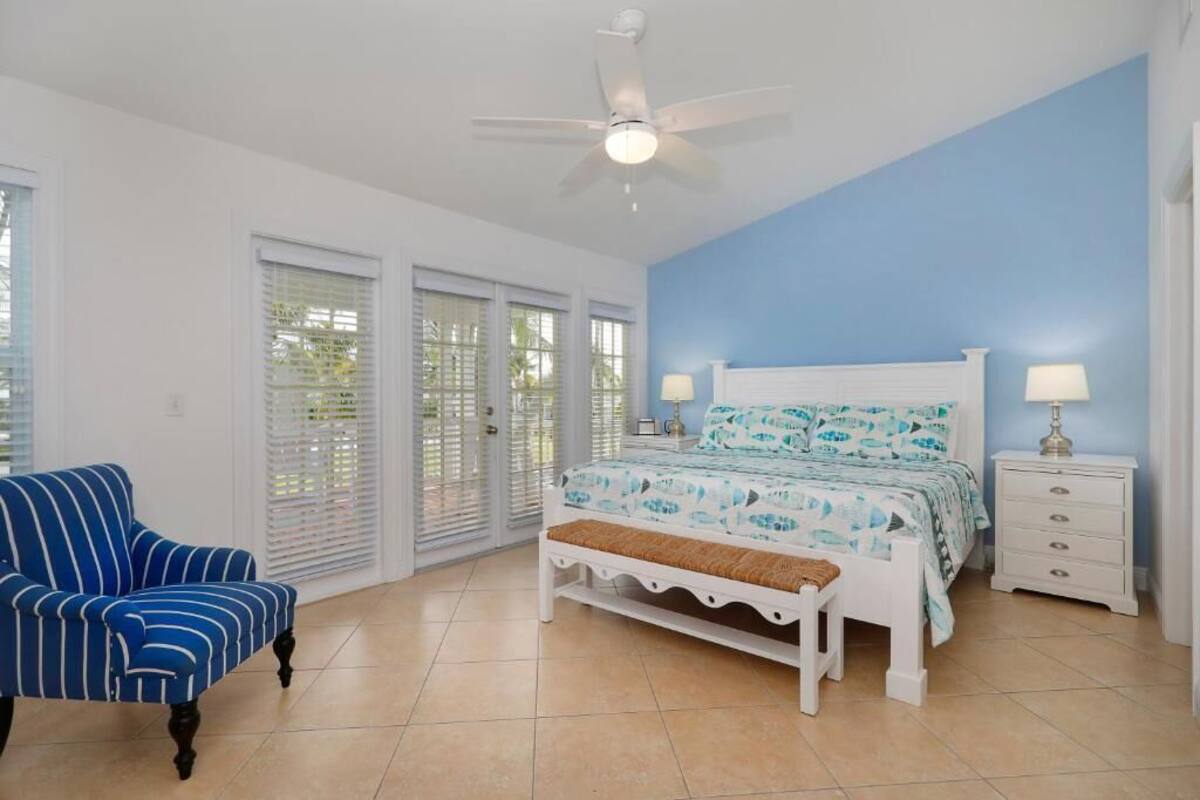 A bedroom with a bed, a chair, a nightstand, and a ceiling fan.