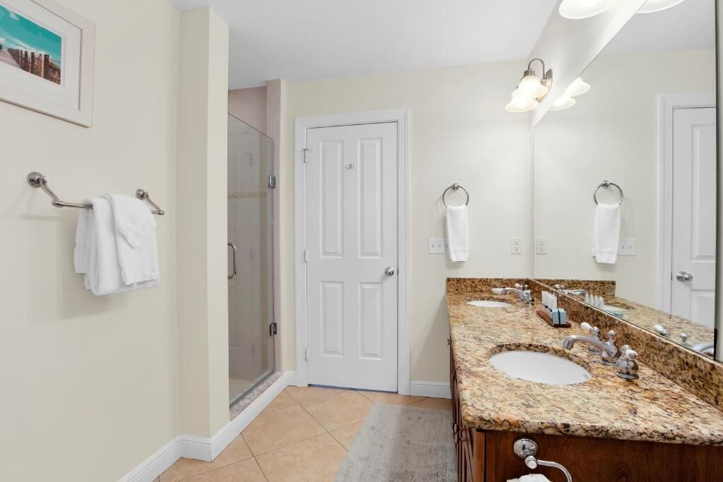 A bathroom with two sinks, a large mirror, and a shower.