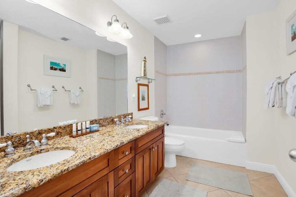 A bathroom with a granite countertop sink, a large mirror, a bathtub, and a shower.
