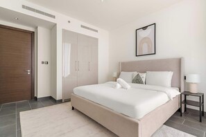 Quarto moderno com uma cama grande, um guarda-roupa, uma mesa de cabeceira e um quadro na parede.