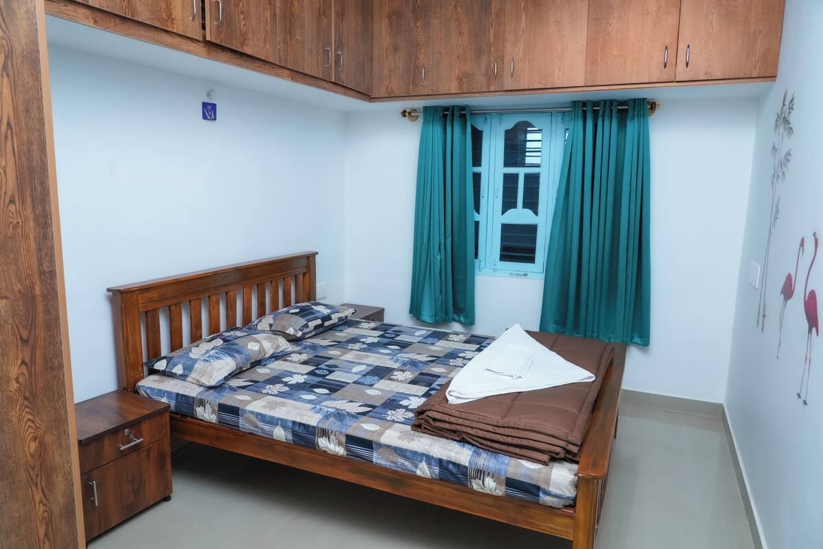 Une chambre à coucher avec un lit en bois, une table de chevet et une fenêtre ornée de rideaux turquoise.