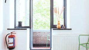 Habitación con extintor, radiador, una silla verde y ventana con vista a follaje.