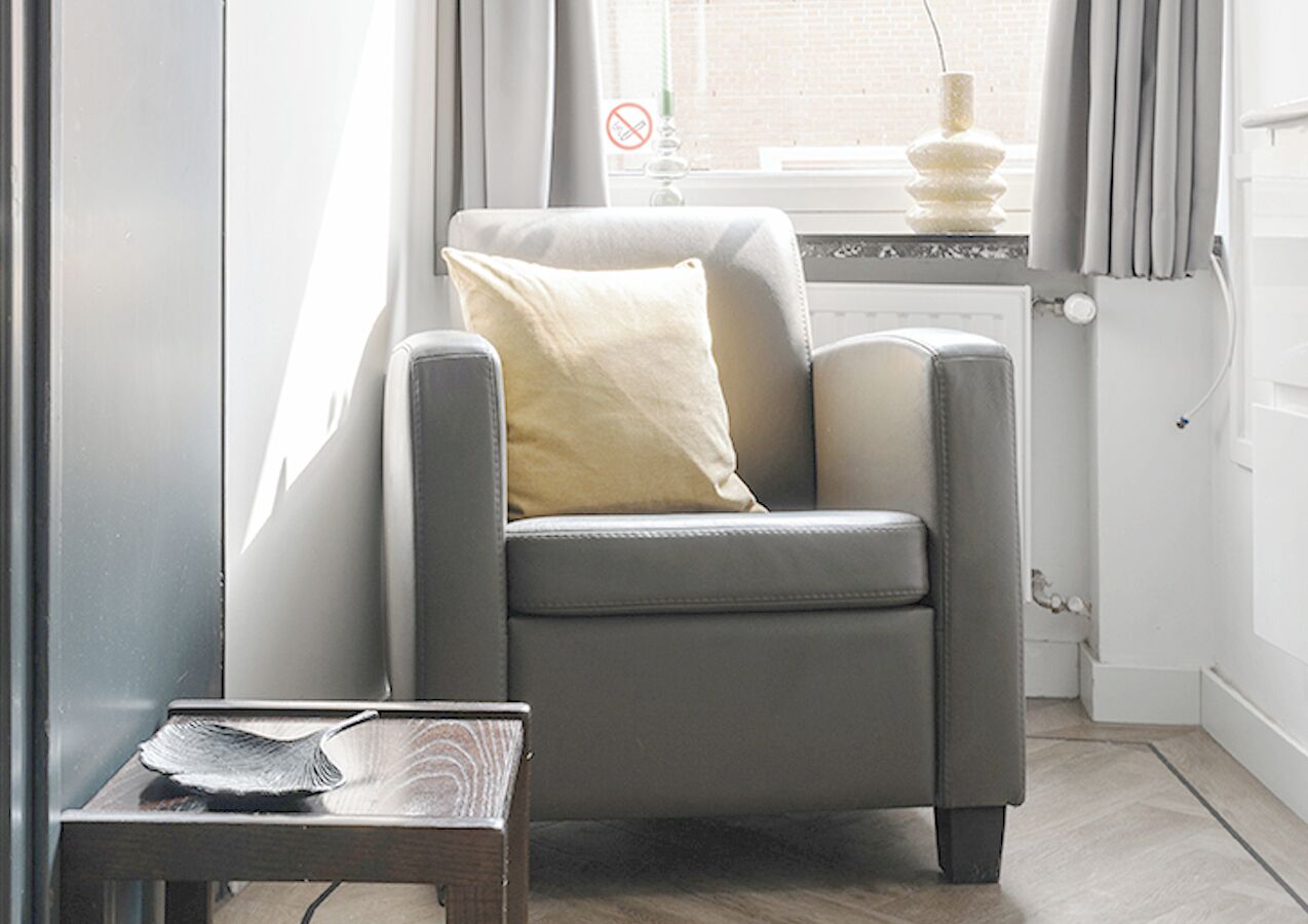 A modern armchair with a cushion, positioned next to a small table with a decorative object.