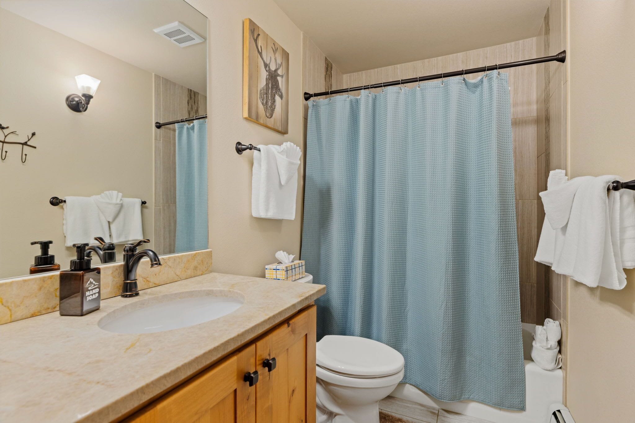 A bathroom with a marble sink, a toilet, a shower curtain, and a mirror.