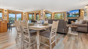 A spacious living room with a fireplace, a television, and a dining area with wooden furniture.