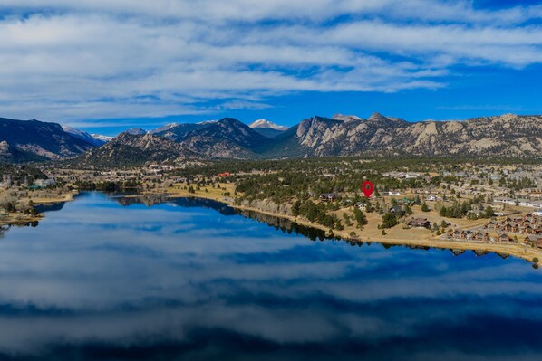 A panoramic view of a town with a lake, mountains in the background, and a red location marker.