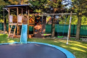 A playground with a slide, climbing wall, and swing set. - Large Holiday Apartment With Sauna (Kołobrzeg)