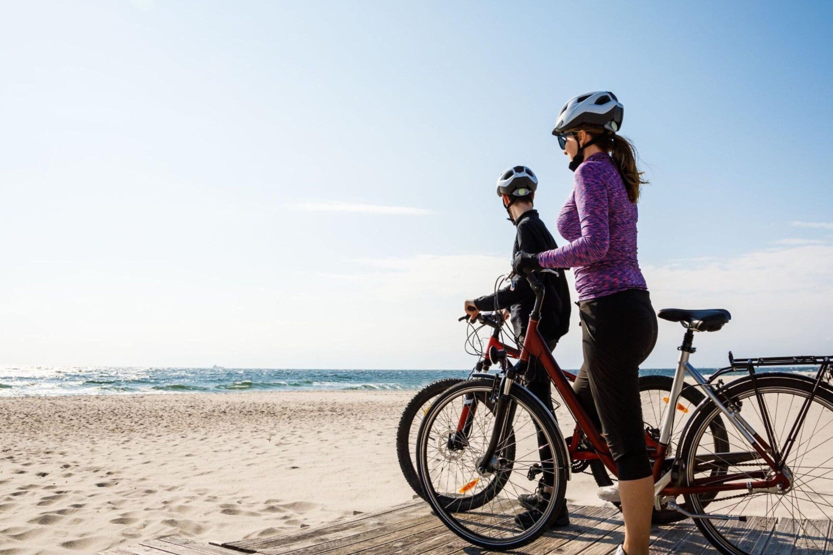 Una spiaggia con due biciclette e una persona che vi sta accanto.