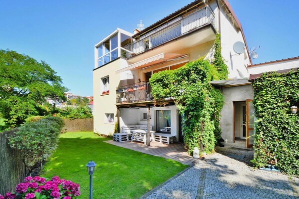 A two-story house with a balcony, a garden, and a patio area.