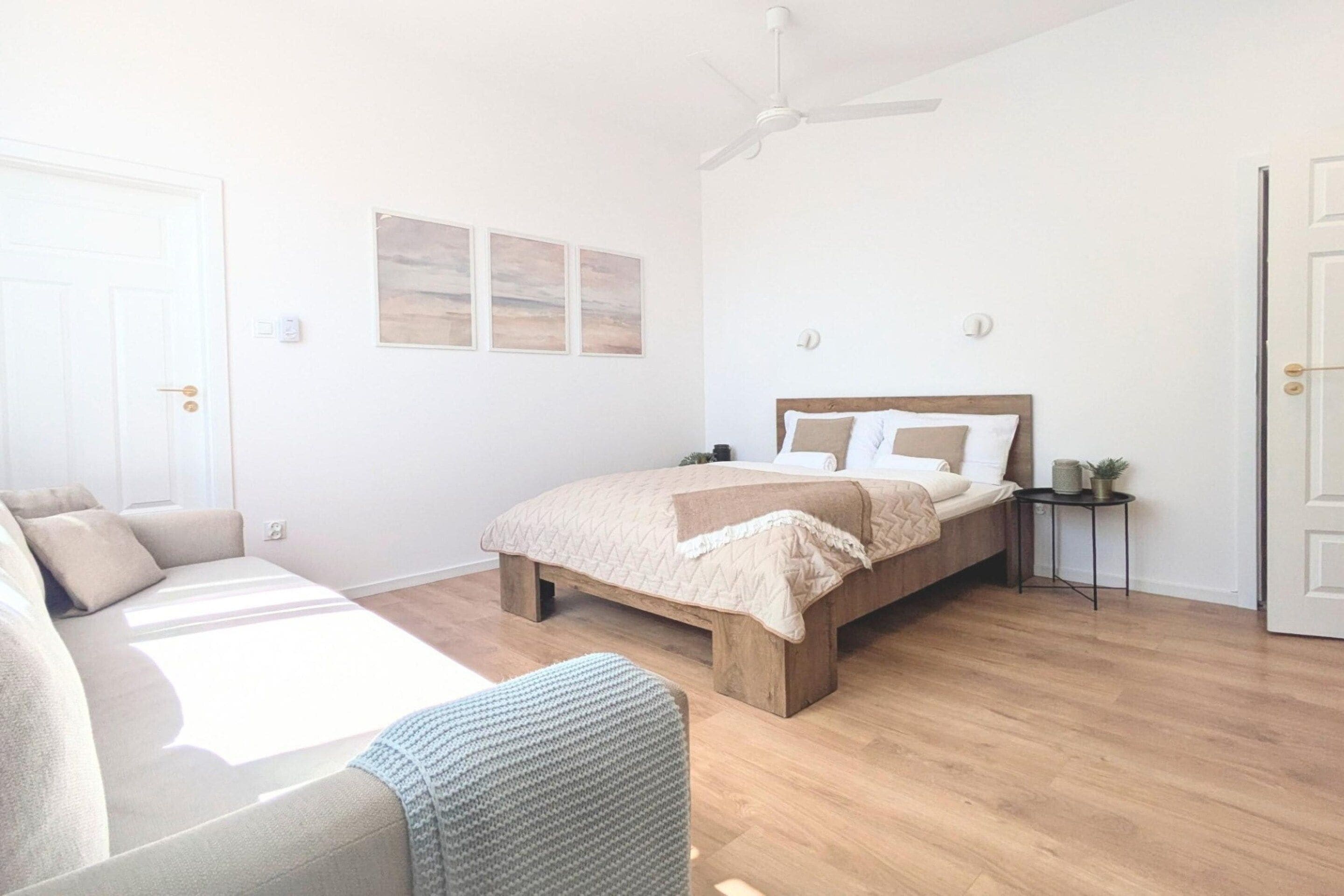 Una camera da letto con un letto, un comodino, una ventola a soffitto e una porta.
