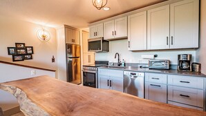 Eine moderne Küche mit Edelstahlgeräten, weißen Schränken und einer Holzausziehtafel.