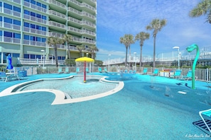 A hotel pool area with a circular water feature, lounge chairs, and palm trees.