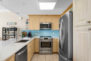 A modern kitchen with a stainless steel refrigerator, a microwave, an oven, and a dishwasher. - NEW Boardwalk Beachfront 603 Updated, Heated Pool, Hot Tub, FREE GOLF & PERKS (Panama City Beach)