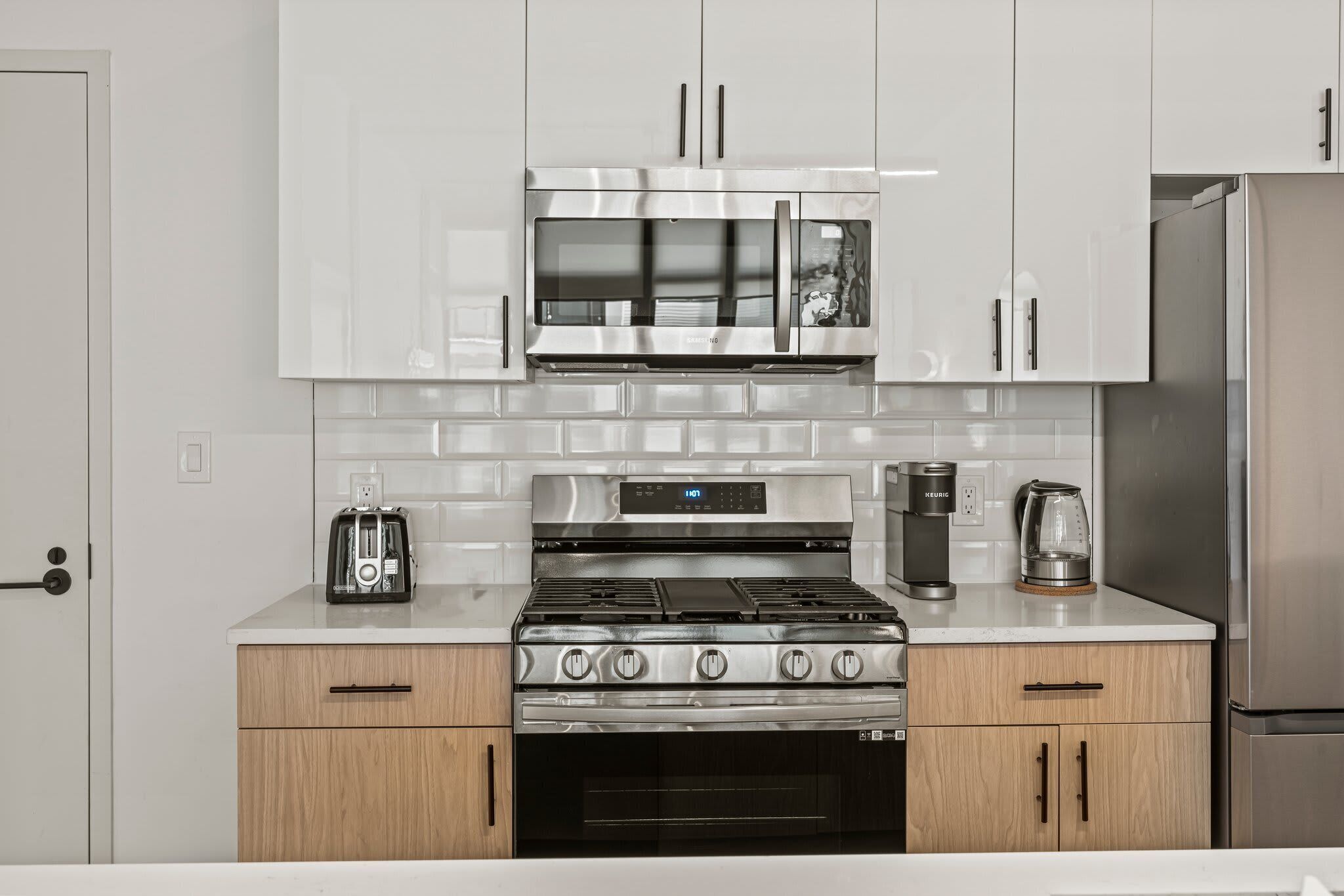 A modern kitchen with stainless steel appliances, white cabinetry, and a built-in oven.