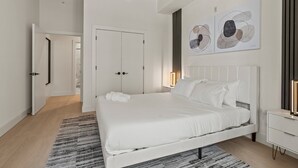 Ein modernes Schlafzimmer mit einem großen Bett, weißen Wänden und abstrakter Kunst.