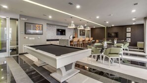 A pool table in a modern room with a bar and seating area.