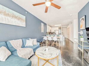 Un salon moderne avec un canapé bleu, une table basse en marbre et un ventilateur de plafond.