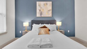 A neatly made bed with white linens, two bedside lamps, and a single decorative pillow. - Luxury 1BD | Uptown | Sleeps 4 | Parking (Dallas)