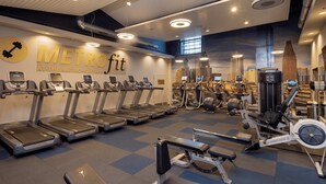 Un gimnasio con cintas de correr, máquinas de pesas y un mural.