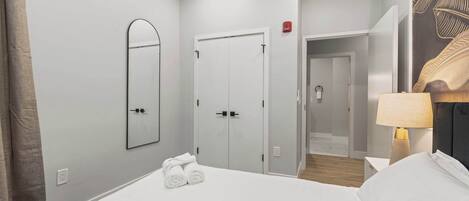 A hotel room with a large bed, a mirror, a wardrobe, and a lamp.