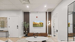 Una sala de estar moderna con una mesa redonda, un sofá, un banco de madera y un cuadro grande en la pared.